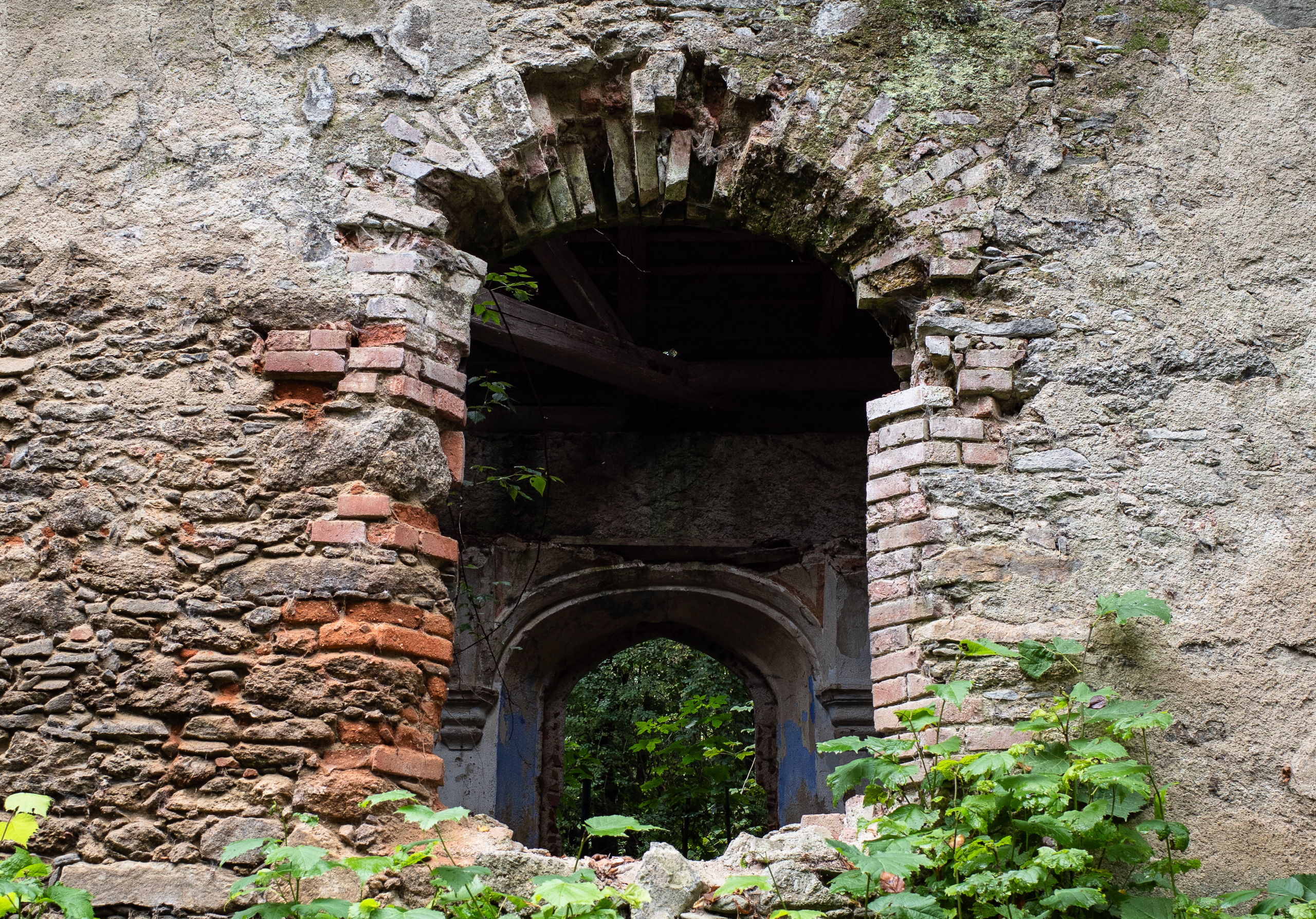 Ruine am Weg: durch den Ziegelbogen wächst der Wald herein